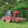 A red tractor with machinery attached to dig through the top layer of soil to aerate it, plus a hopper to spread seeds.