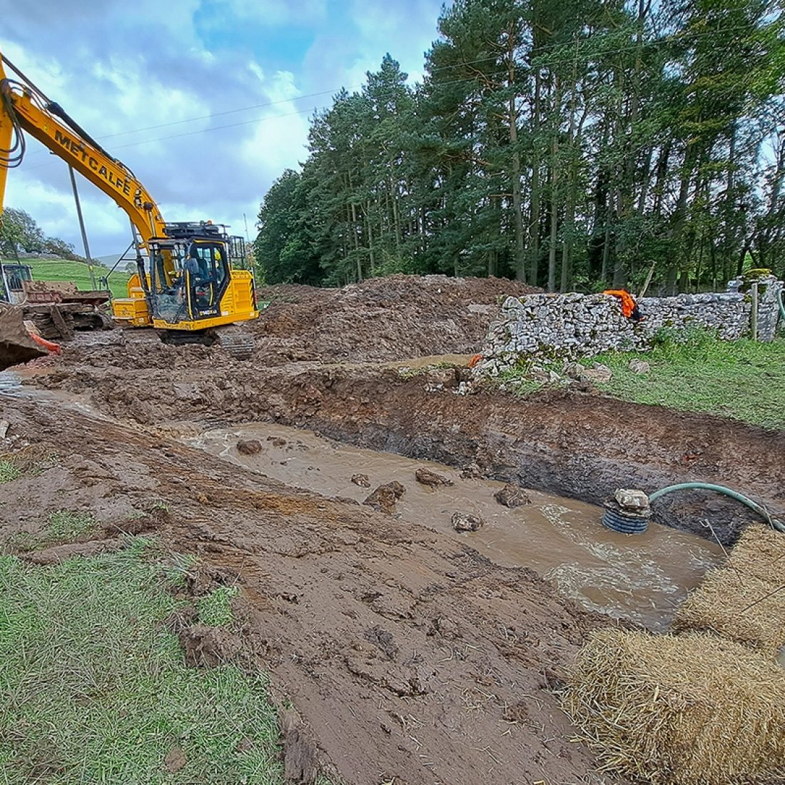 Hay bales and a pump in place to capture sediment as the new/existing channels are connected.