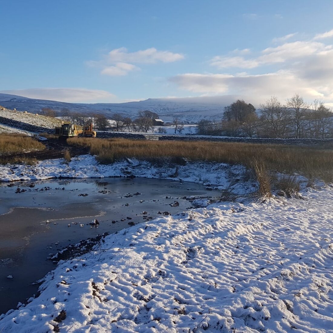 One of the new scrapes. It's a winter's day, so there is little water in the pond and snow has settled on the bank.