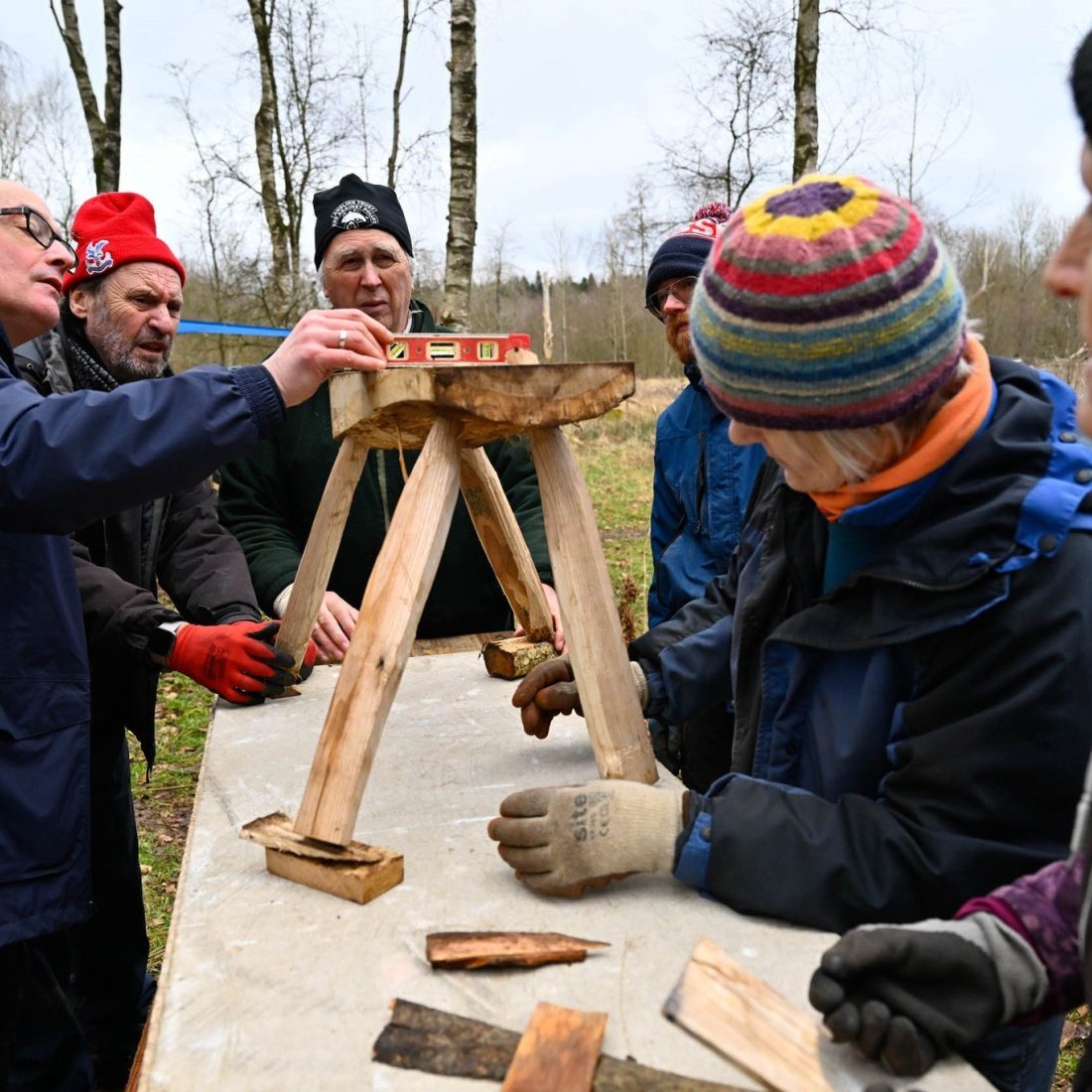 A group of volunteers with a wooden stall, balancing and levelling its legs for stability.