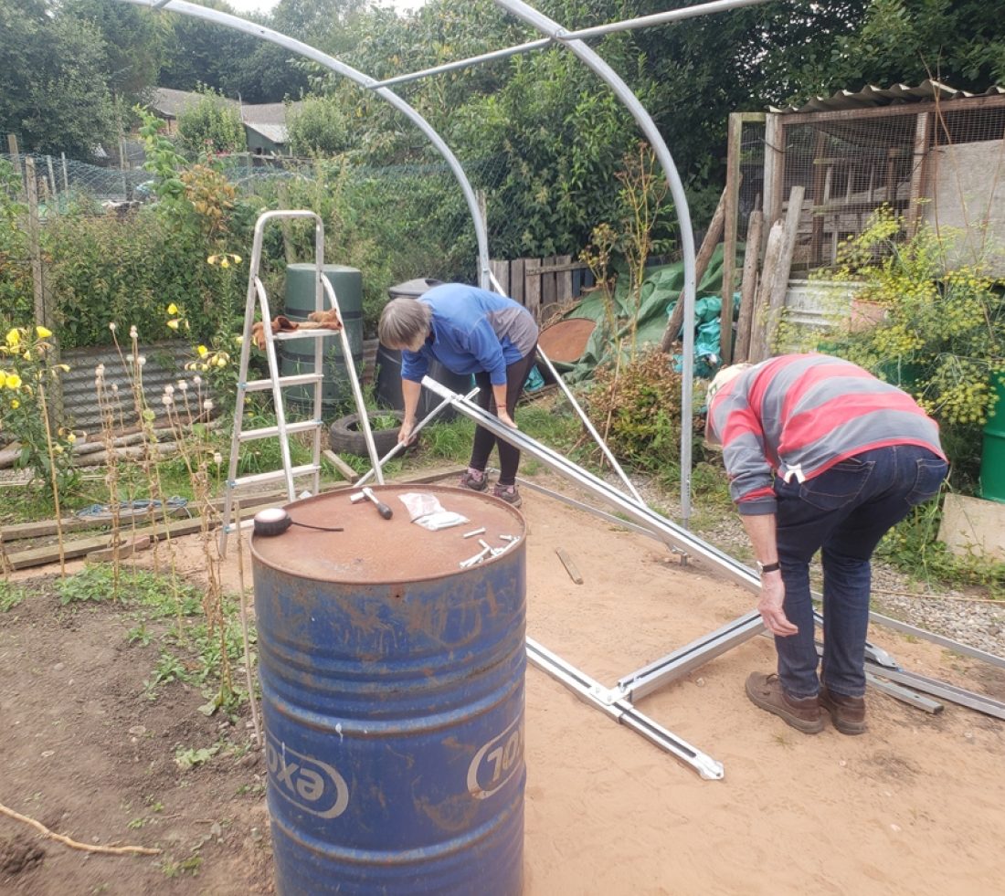 Two volunteers constructing the framework for a new polytunnel.