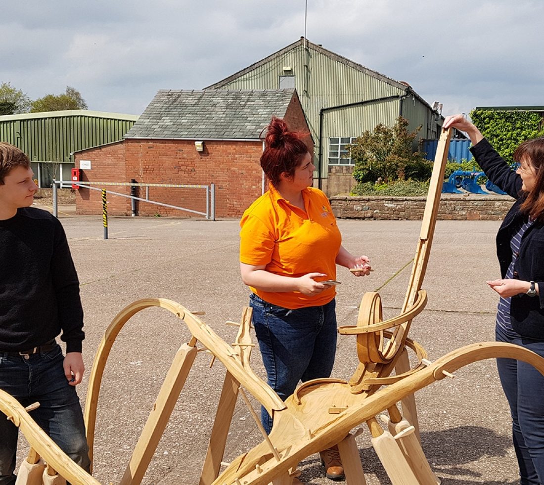 Photograph of three people stood next to a wooden section of a marble run.