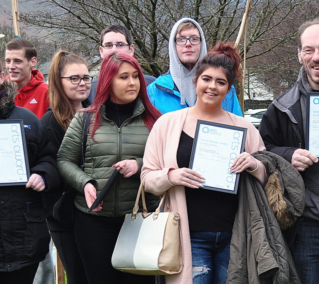 A group of young people posing for a photograph, holding 'Art Award' framed certificates.