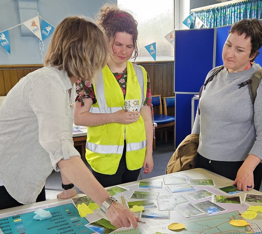 Members of the public having a discussion and looking at a site map during an indoor consultation event.