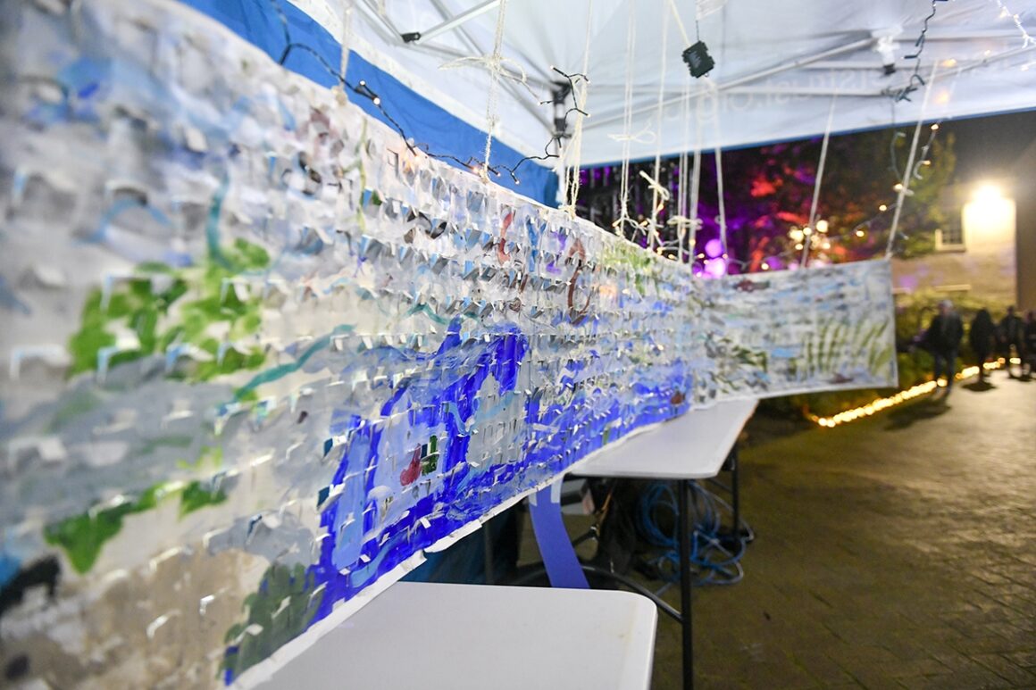 Close up view of a 4 metre long cross section of a river painted with collage pieces added, illuminated by lighting under an ERT awning.