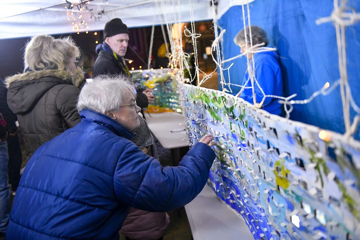 View of people looking at art exhibit inside illuminated awning.