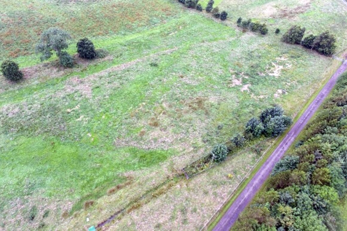Aerial view of a straightened river channel through grass field.