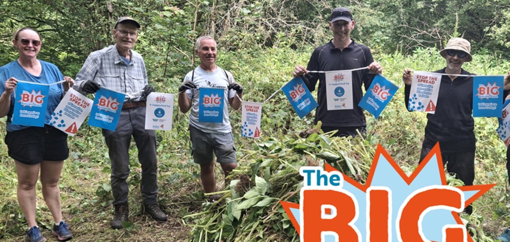 Image of volunteers standing behind a pile of uprooted balsam with a logo in the corner which reads: 