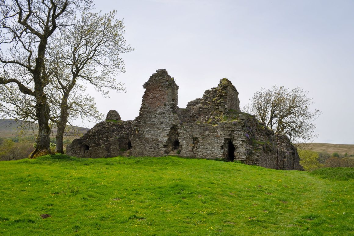 View of Pendragon Castle across green field.