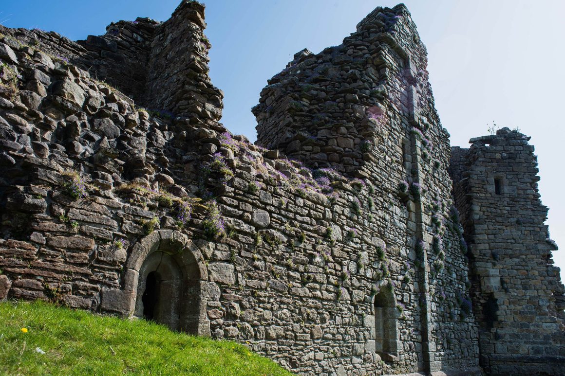 Derelict stone walls of Pendragon Castle featuring arched doorways .