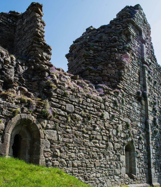 Derelict stone walls of Pendragon Castle featuring arched doorways .