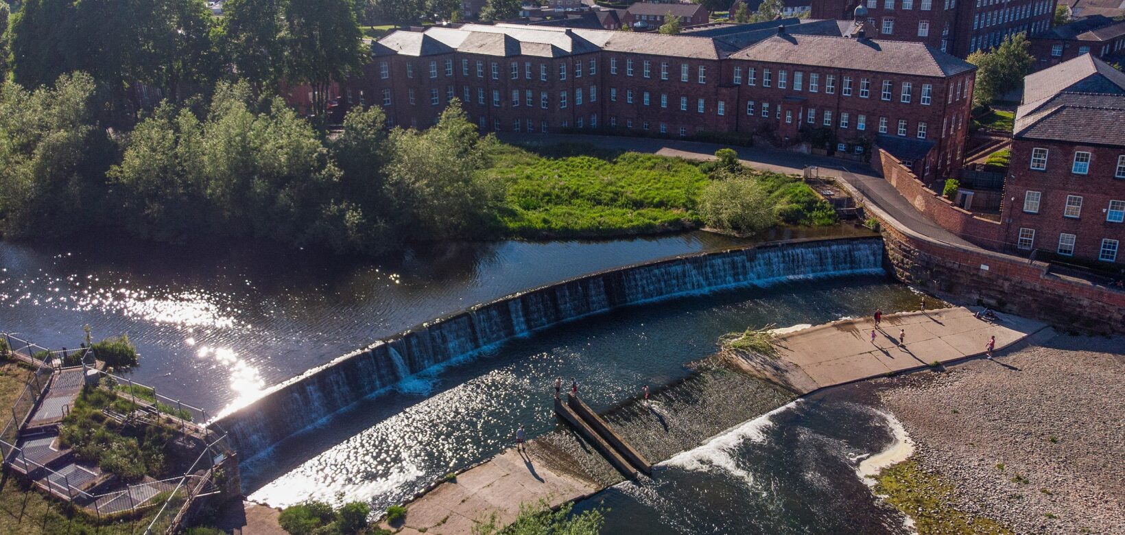 Aerial view of a large weir with houses behind it