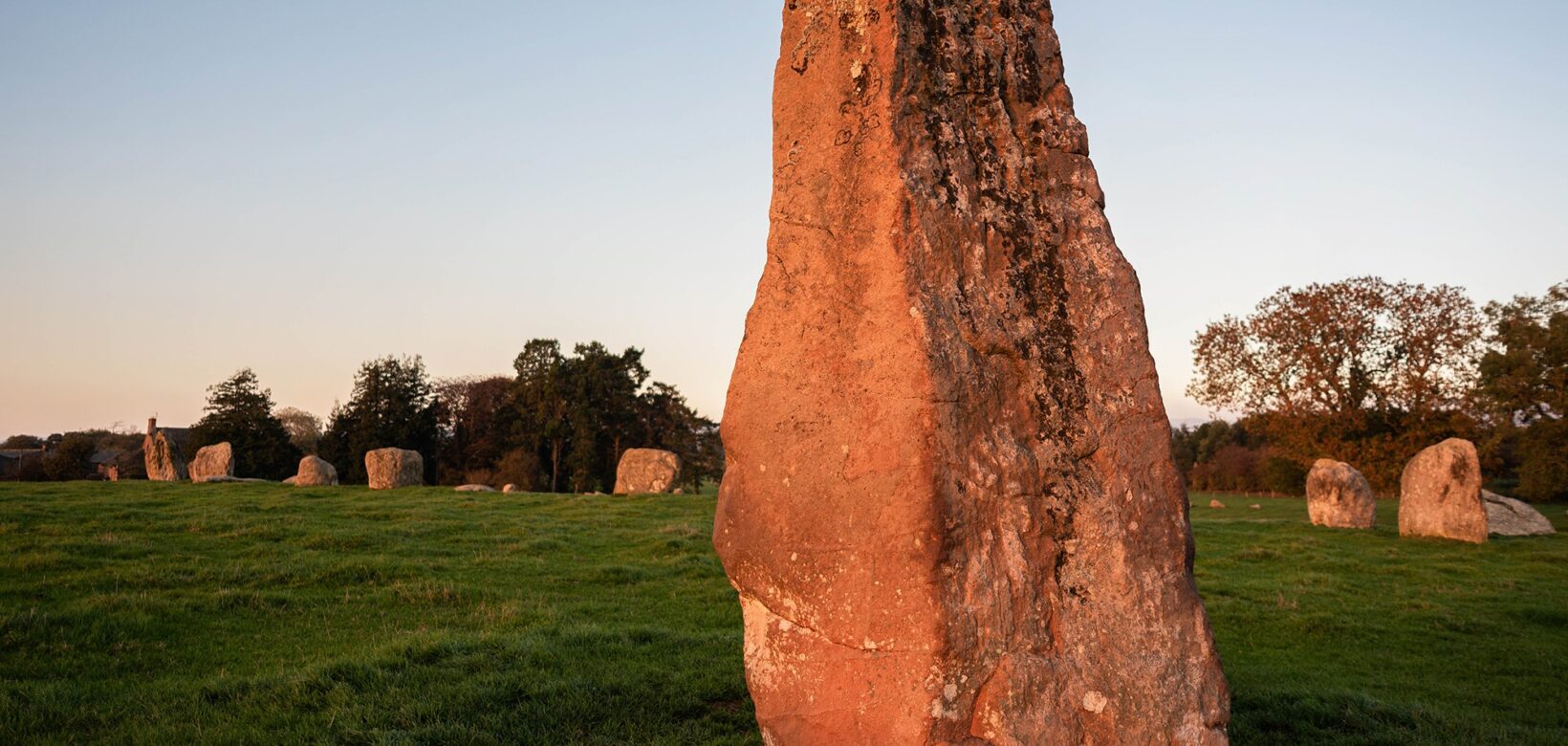 A row of stones makes a circle. In the foreground is a much taller stone, called Long Meg that is outside the circle.