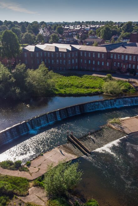 Aerial view of a large weir with houses behind it