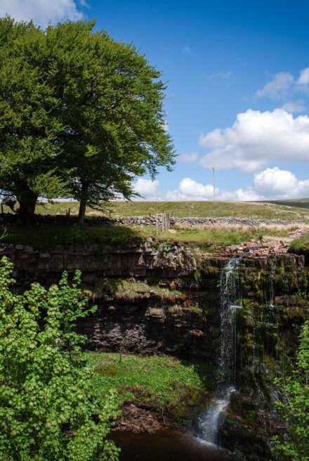 Water run off from fields cascading over high river bank into small gorge.