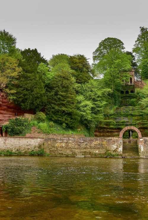 Across the River Eden, cut into the hillside lies Corby cascade, a waterfall behing a stone wall and gate and caves carved into red standstone.