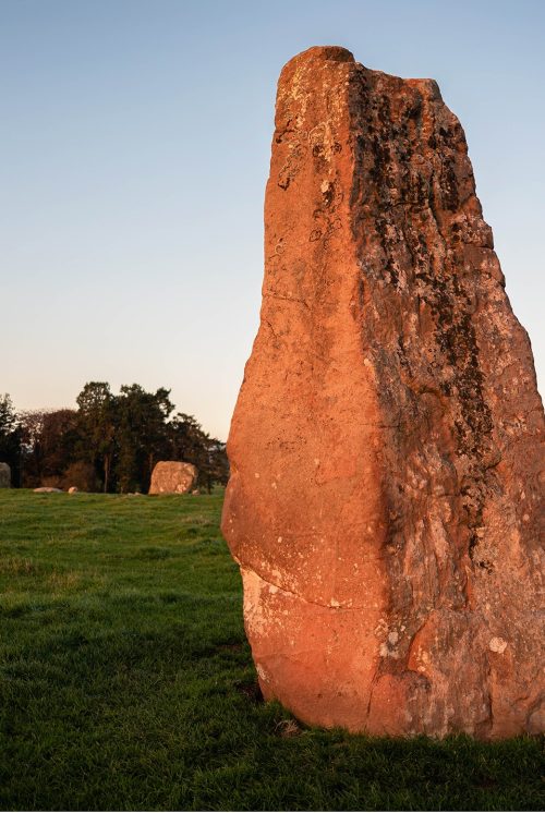 A row of stones makes a circle. In the foreground is a much taller stone, called Long Meg that is outside the circle.