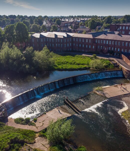 Aerial view of a large weir with houses behind it