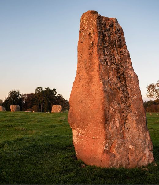 A row of stones makes a circle. In the foreground is a much taller stone, called Long Meg that is outside the circle.