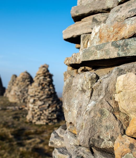 Five stone cairns are shown on top of a hill