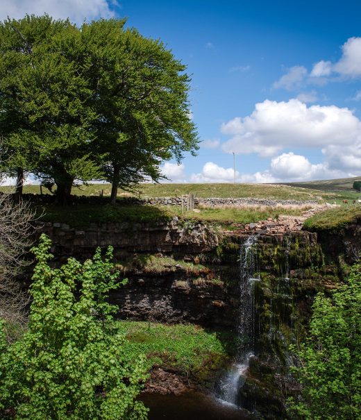 Water run off from fields cascading over high river bank into small gorge.