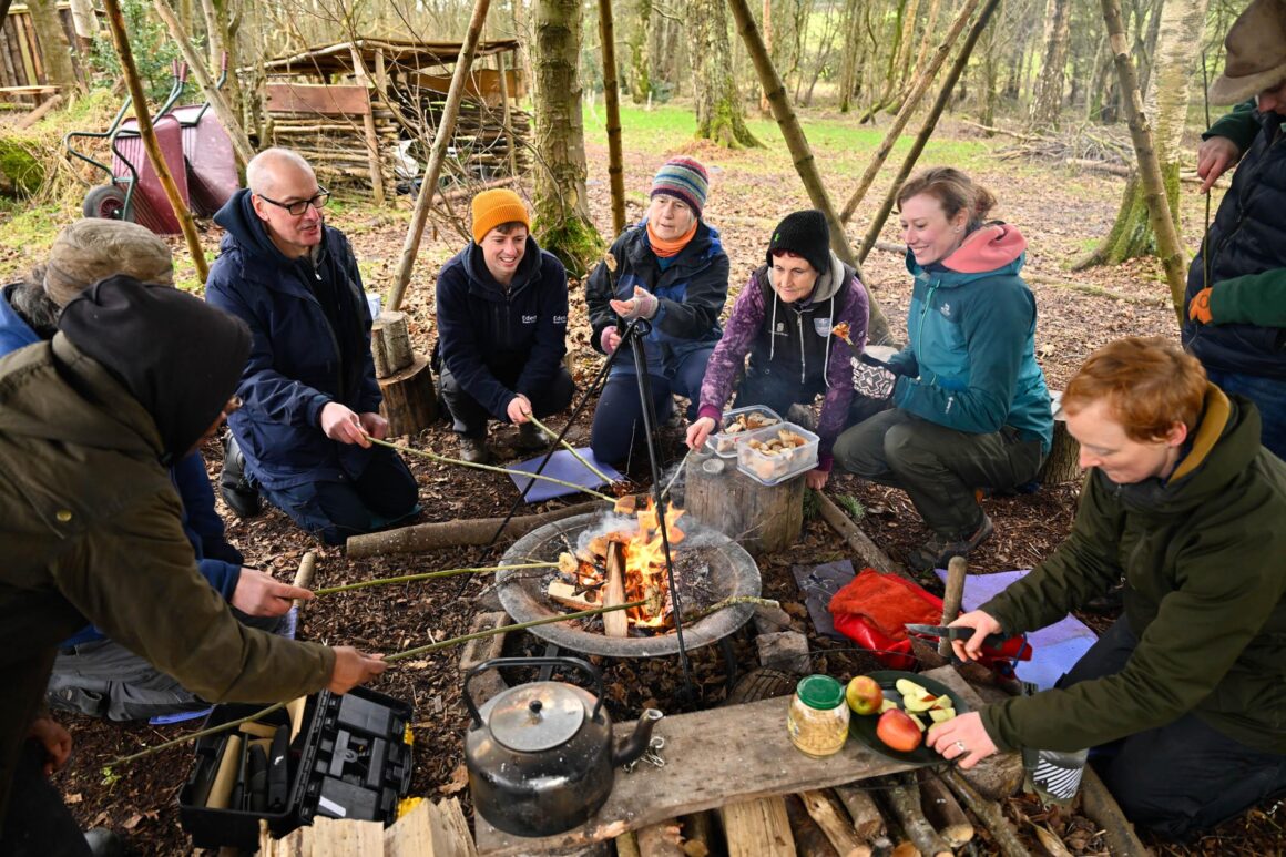 Volunteers sat around a firepit cooking marshmallows on wooden sticks.
