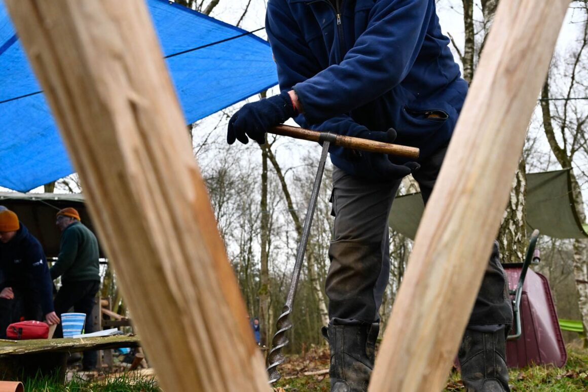 A volunteer works on the legs of an upturned wooden bench to get them level.