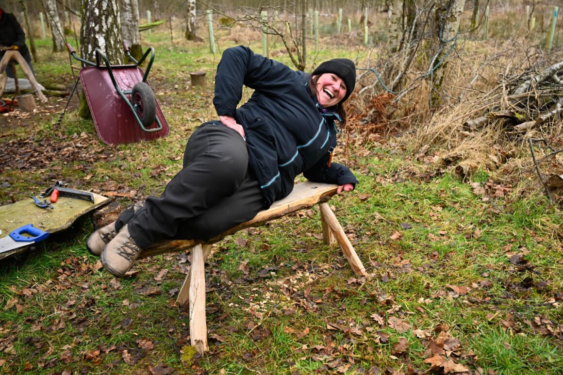 A volunteer lying on a newly built wooden bench.