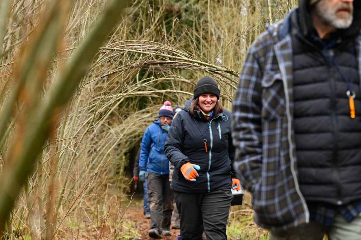 Volunteers walking through a willow archway.