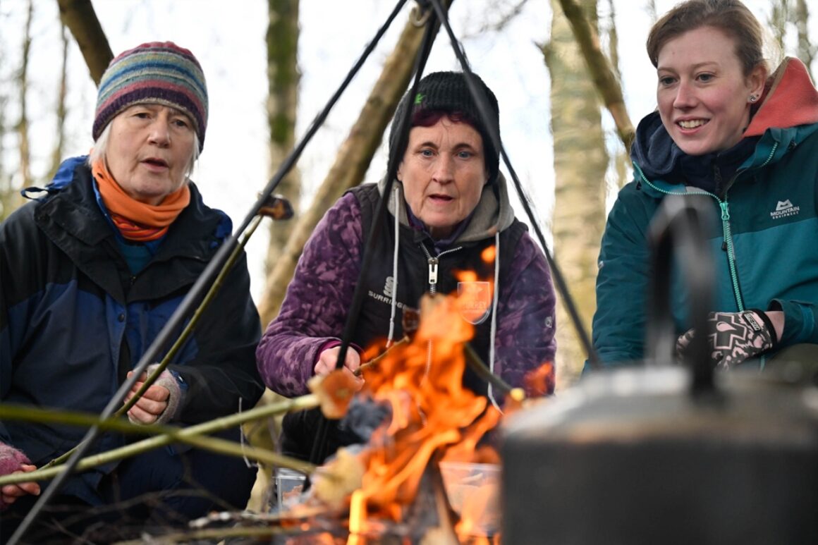 Volunteers and ERT staff sat around a firepit cooking marshmallows on wooden sticks.