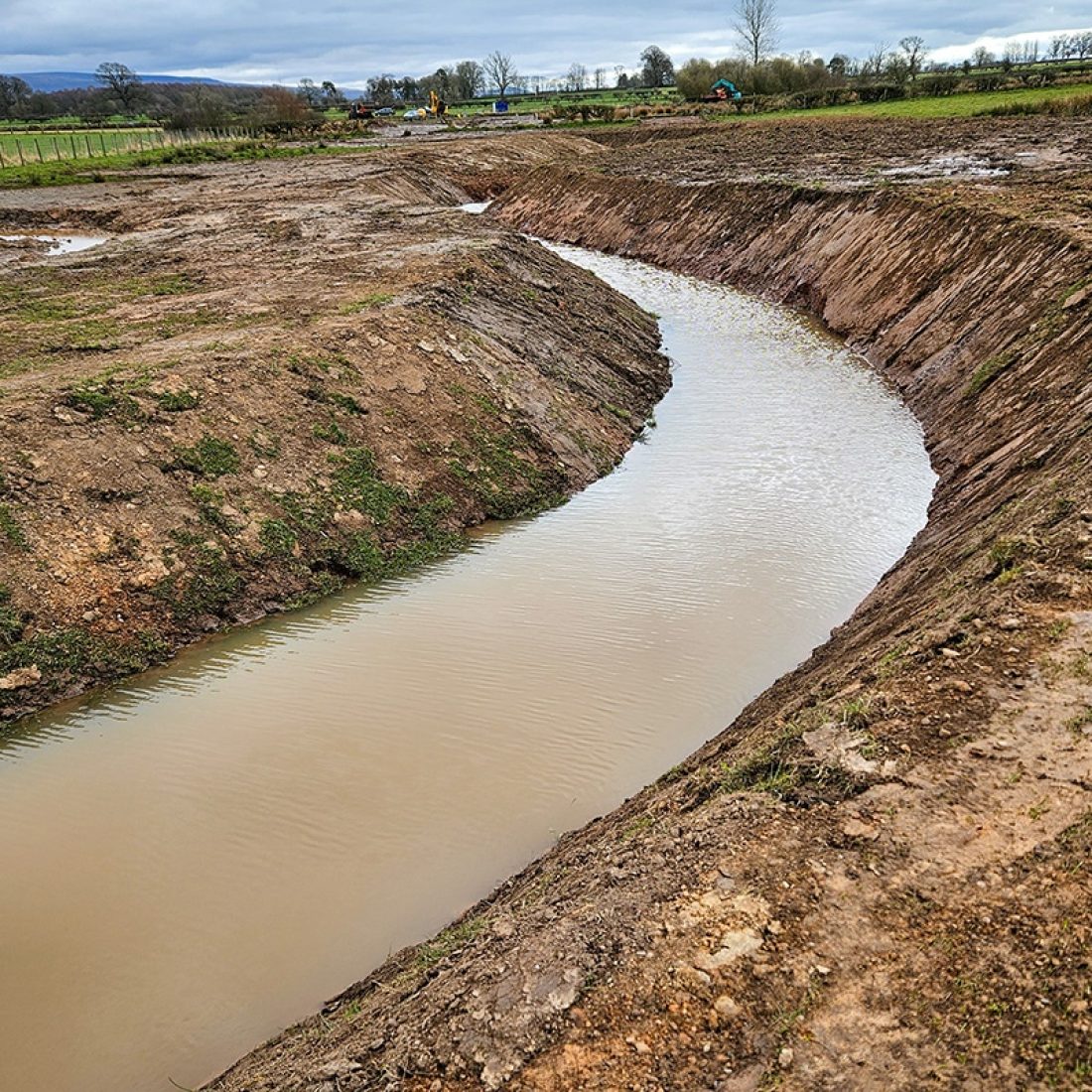 A new river channel excavated to put the wiggle back into the route of the watercourse to slow the flow of water and improve habitat.