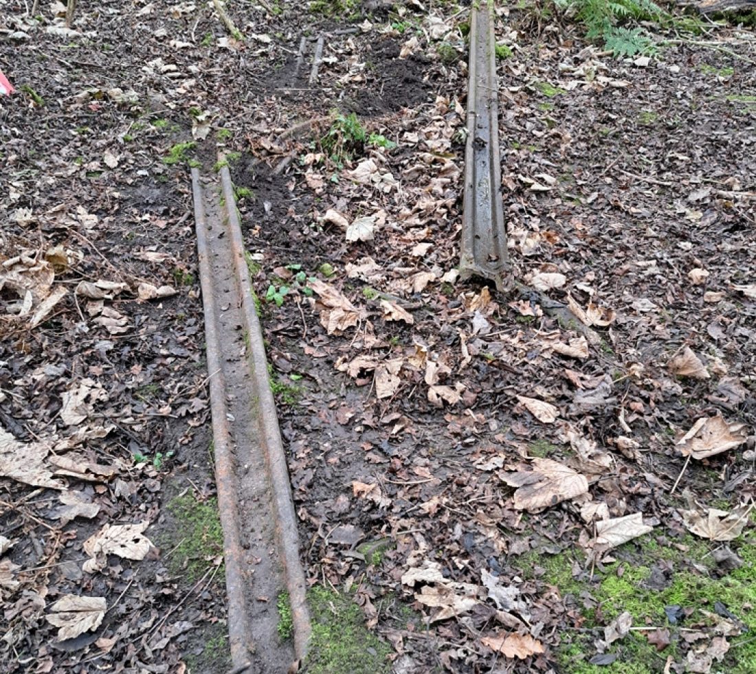 Sections of obsolete railway track half buried in soil. Part of a railway track leading to a rail yard once active on the site.