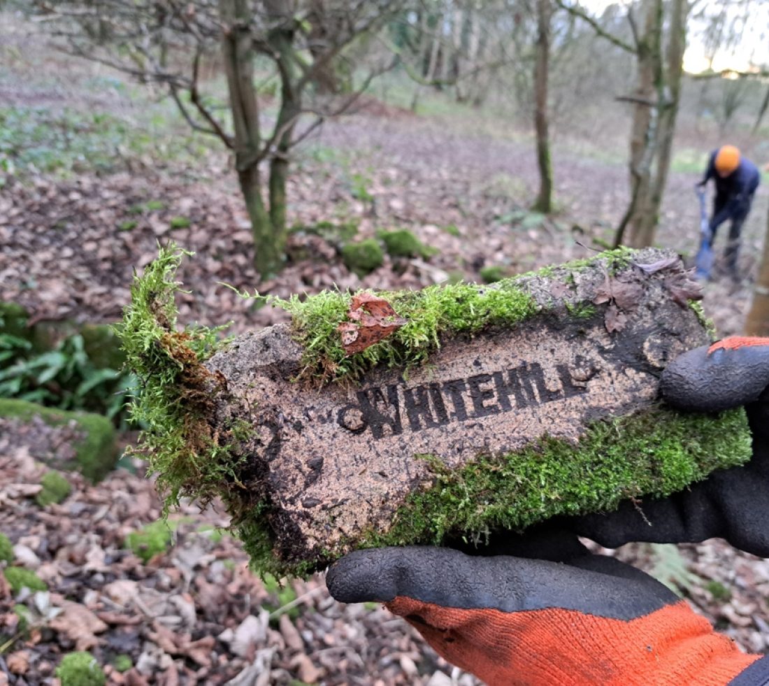 A volunteer holding a stone brick with the word Whitehill stamped onto its surface.