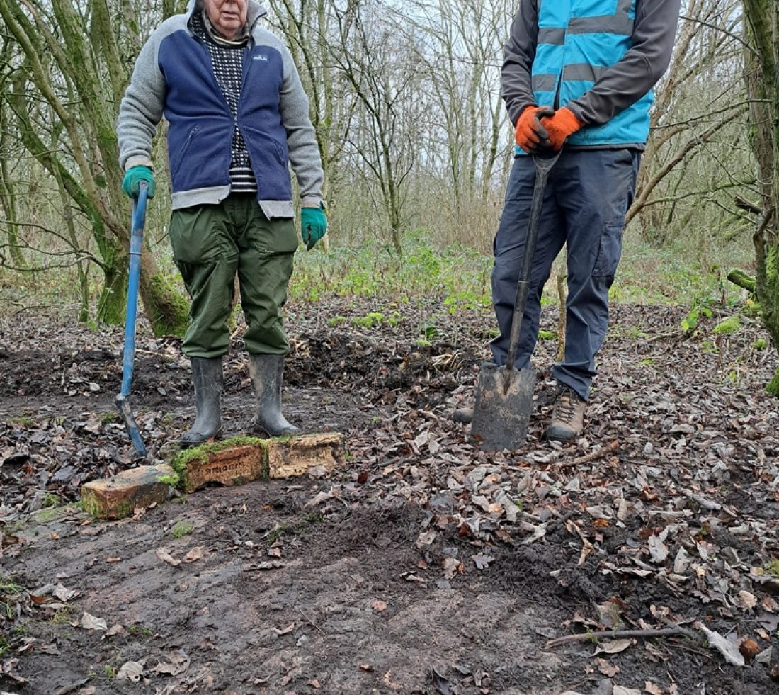 Volunteers stood next to a section of brick flooring unearthed during undergrowth clearance work. This would have formed the floor of a former rail yard building on the site.