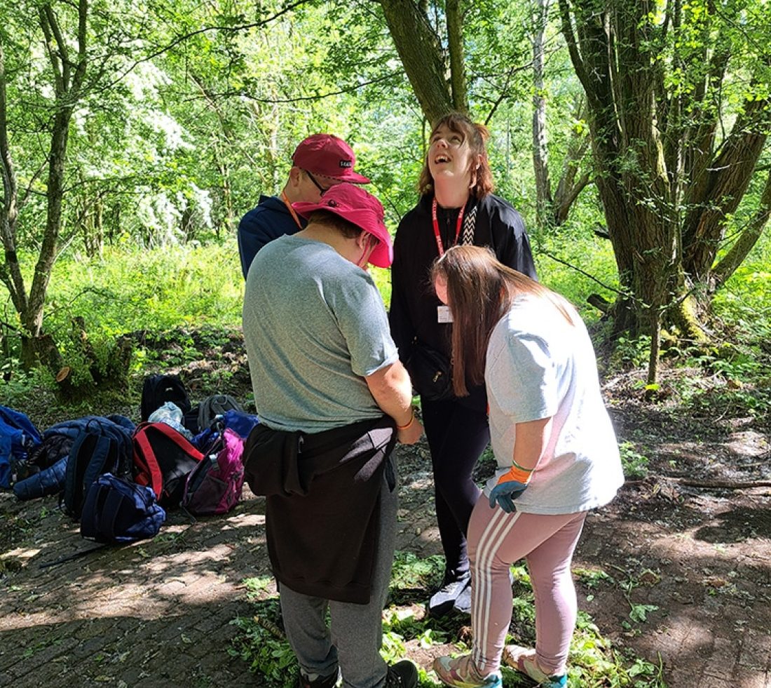 A group of volunteers stamping on a pile of uprooted Himalayan balsam plants.