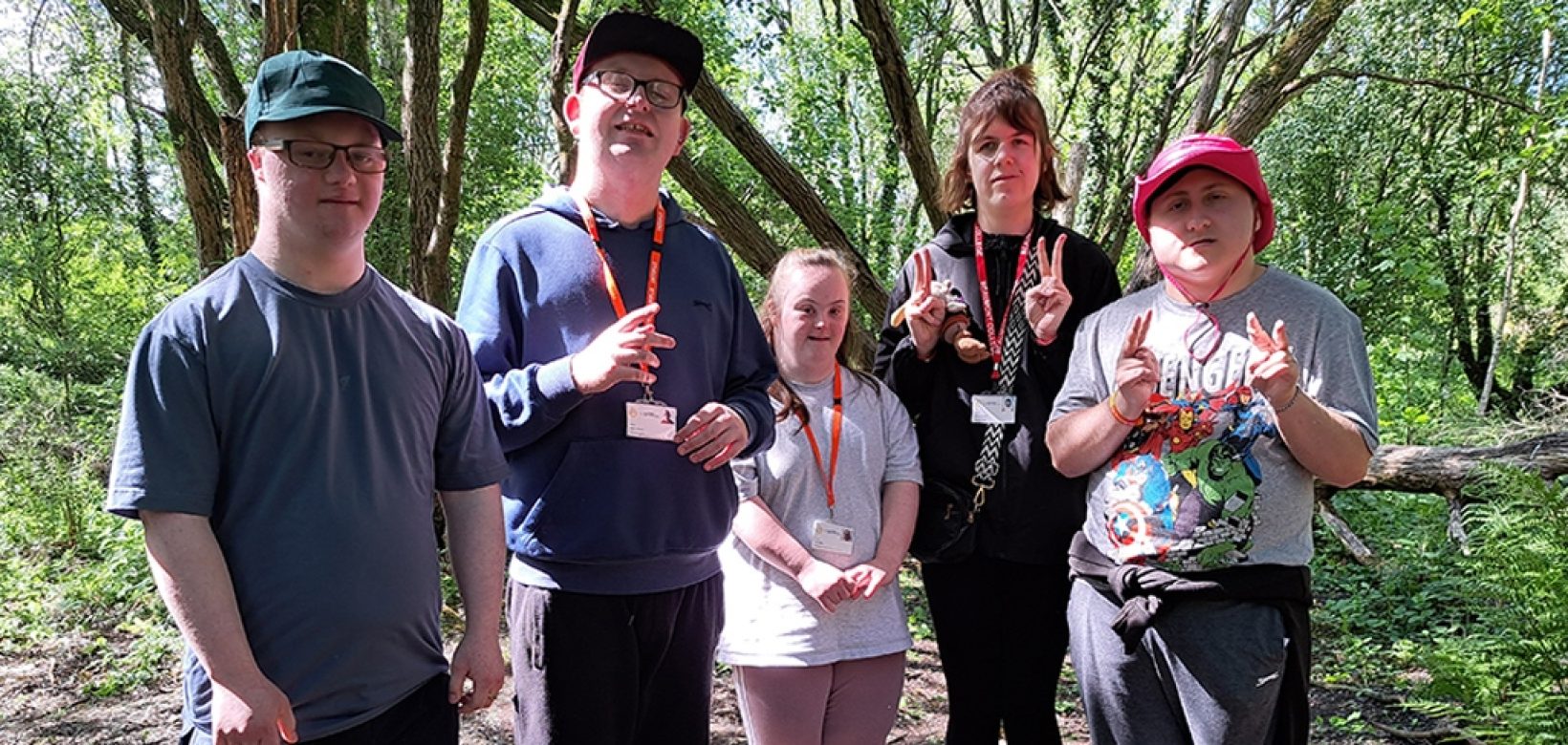 A group of balsam bashing volunteers posing for a group photograph in woodland at Engine Lonning.