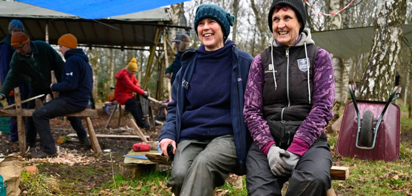 ERT staff member and volunteer sitting on a wooden bench made as part of a woodland skills session provided at the ERT volunteer celebration day.