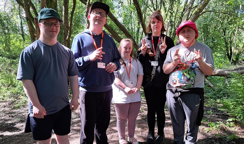 A group of balsam bashing volunteers posing for a group photograph in woodland at Engine Lonning.