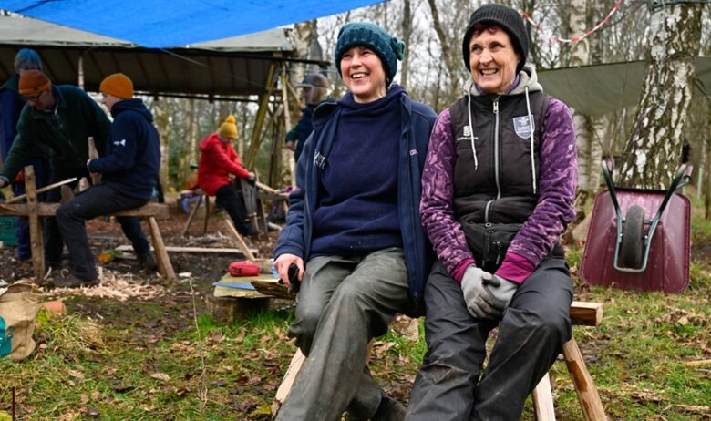 ERT staff member and volunteer sitting on a wooden bench made as part of a woodland skills session provided at the ERT volunteer celebration day.