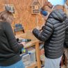 A group of young people in a woodworking workshop drilling and constructing a wooden bird box.
