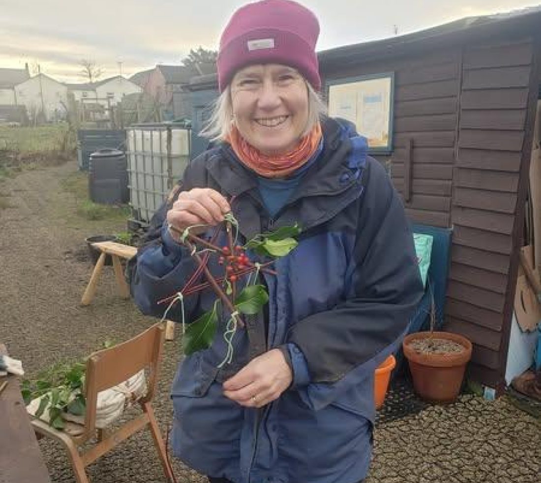 A volunteer at the Penrith Community Tree Nursery posing for a photograph holding a willow star Christmas decoration.