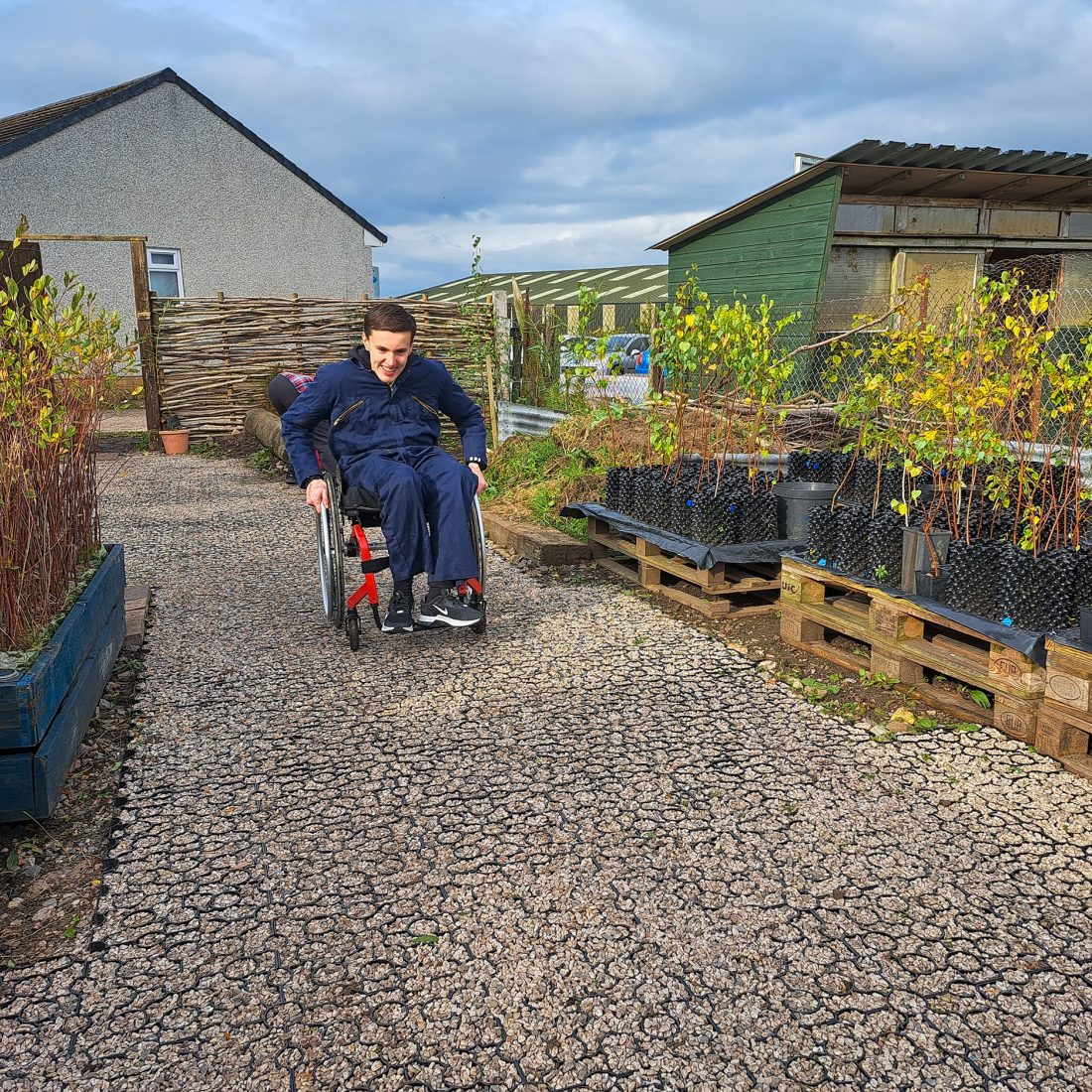 A wheelchair user testing out a newly-laid accessible path at the Eden Community Tree Nursery