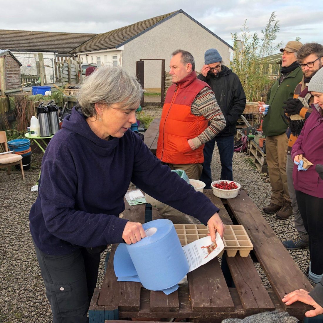 A group of volunteers assembled around wooden table at the Penrith Community Tree Nursery.