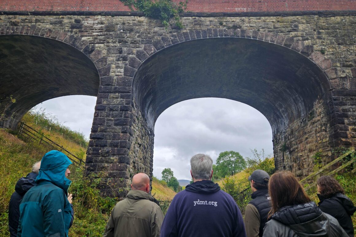 Staff members from Cumbria Wildlife Trust, Yorkshire Dale National Park Authority and Eden Rivers Trust standing on the Podgill viaduct trail path looking up at the Podgill viaduct structure.