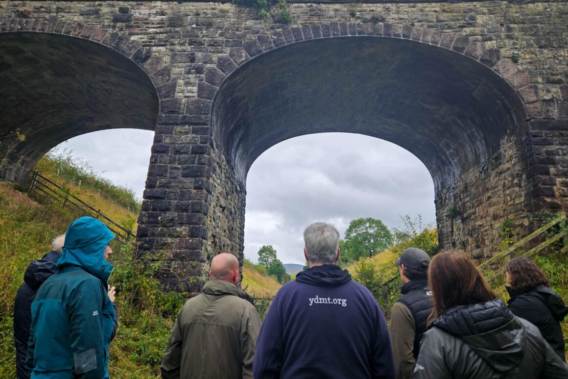 Staff members from Cumbria Wildlife Trust, Yorkshire Dale National Park Authority and Eden Rivers Trust standing on the Podgill viaduct trail path looking up at the Podgill viaduct structure.