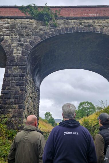 Staff members from Cumbria Wildlife Trust, Yorkshire Dale National Park Authority and Eden Rivers Trust standing on the Podgill viaduct trail path looking up at the Podgill viaduct structure.
