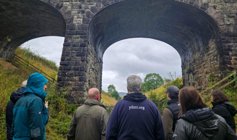 Staff members from Cumbria Wildlife Trust, Yorkshire Dale National Park Authority and Eden Rivers Trust standing on the Podgill viaduct trail path looking up at the Podgill viaduct structure.