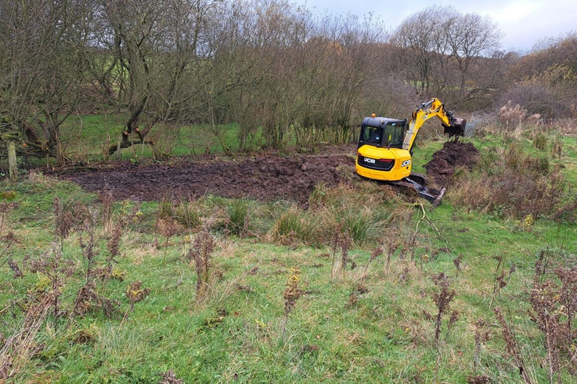Groundwork underway on Wallacefield site. A digger is moving soil to redirect existing river channel.