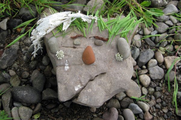 Stones and a large boulder arranged in the shape of a face with grass for hair.