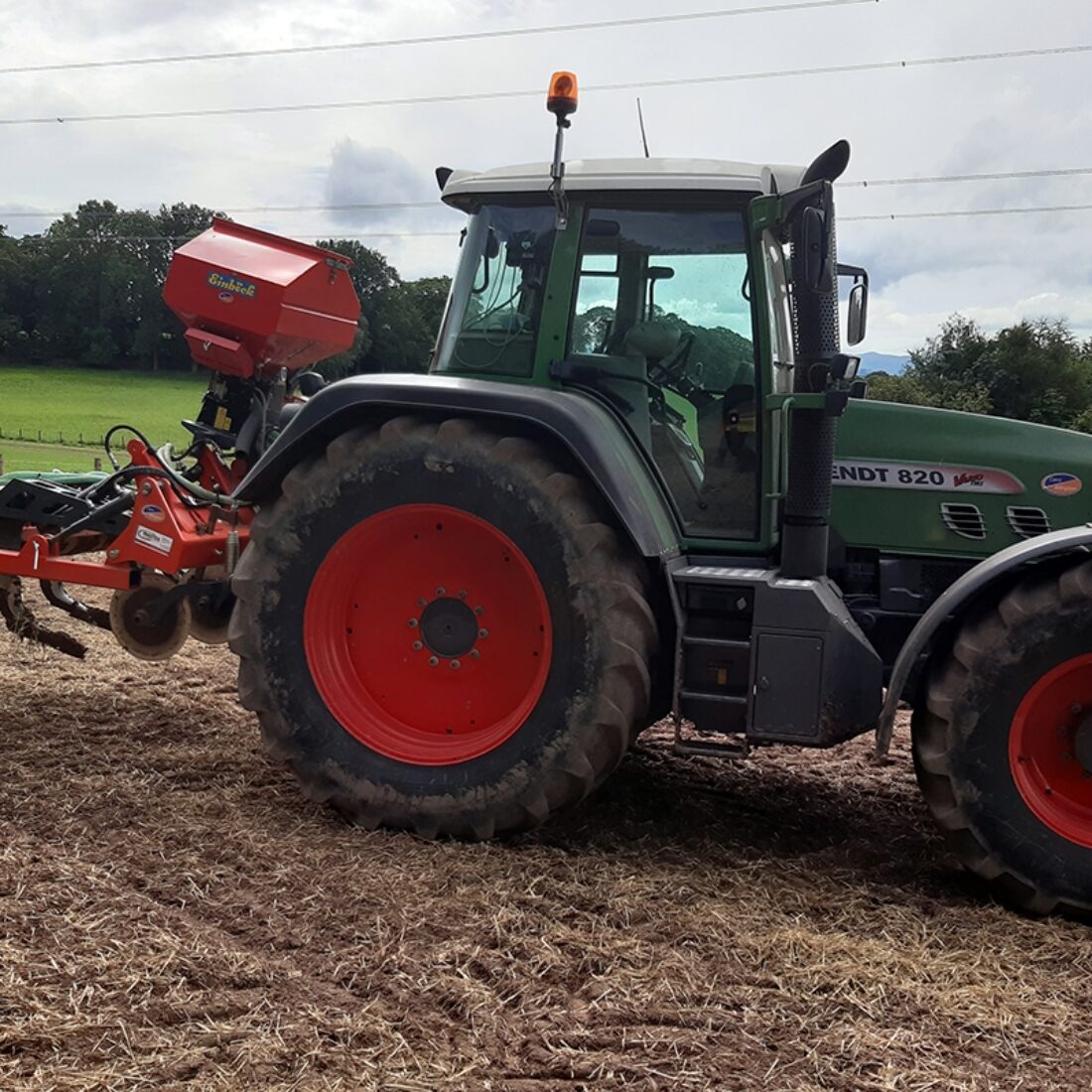 Tractor in muddy field with plough equipment attached.